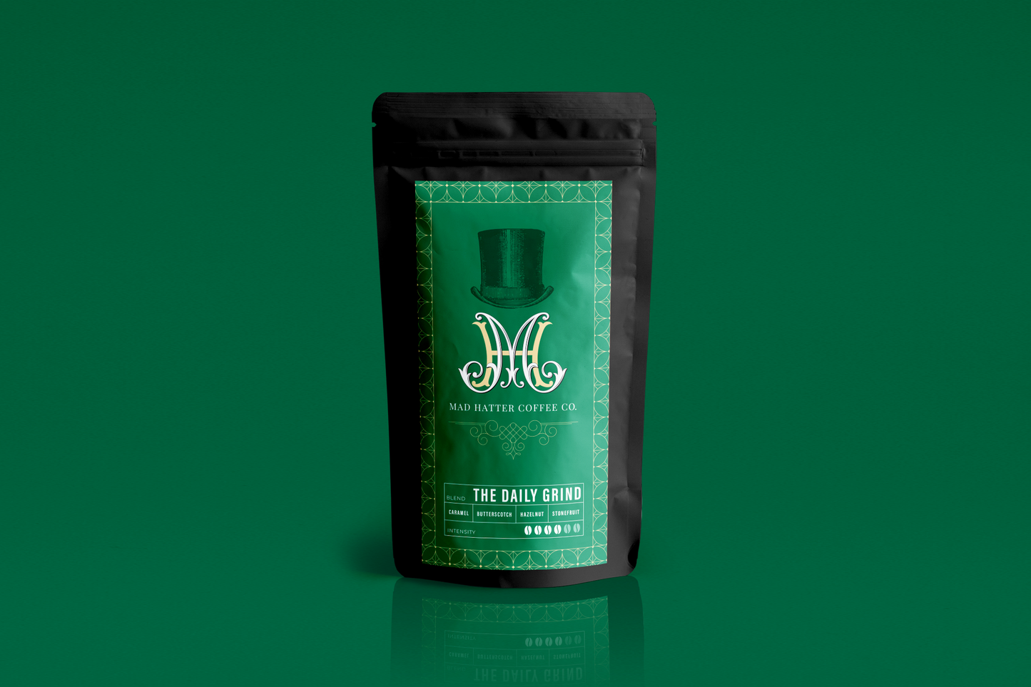 Mad Hatter Coffee Co. 'The Daily Grind' blend in sleek black and green packaging, featuring caramel, hazelnut, and stone fruit notes.